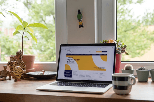Ordinateur portable affichant un site web professionnel sur un bureau près d’une fenêtre