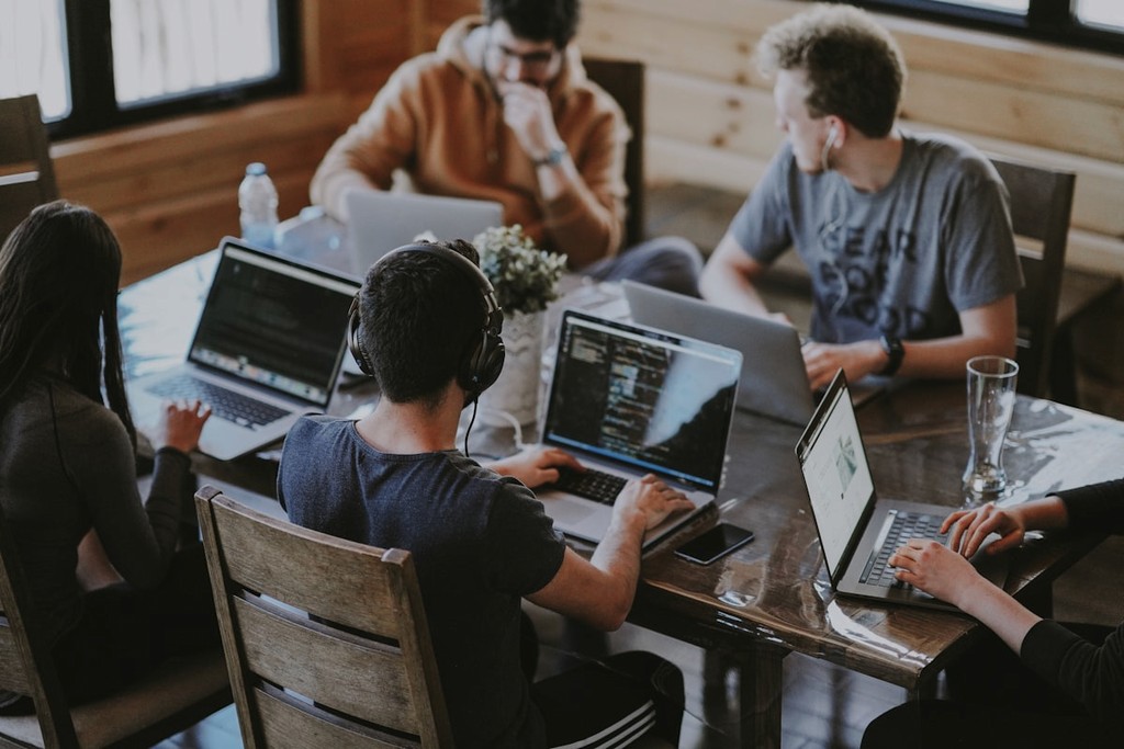 Agence web en collaboration – équipe de développeurs travaillant sur la création de sites web et projets numériques sur ordinateurs portables