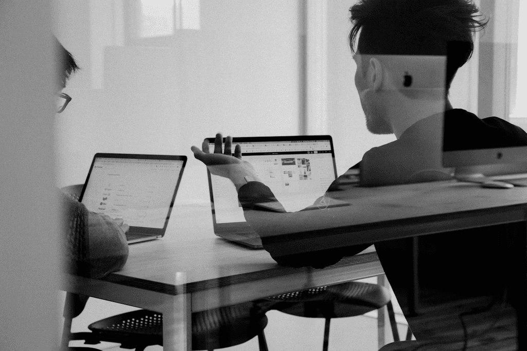 Deux professionnels analysant les performances d’un site web sur ordinateur portable lors d’une réunion stratégique marketing.
