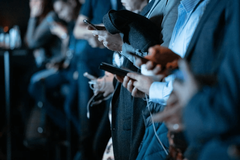 Groupe de professionnels debout utilisant leurs téléphones intelligents lors d’un événement ou d’une conférence.